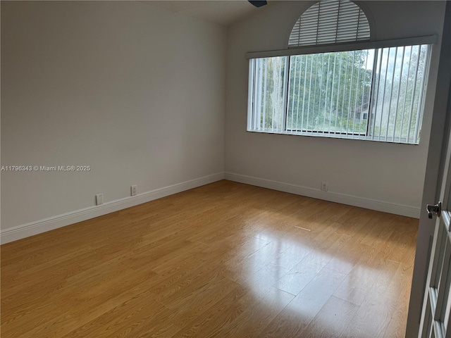 unfurnished room with baseboards, light wood-style flooring, and vaulted ceiling