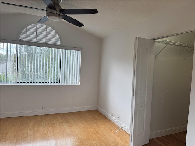 unfurnished bedroom featuring ceiling fan, light wood-type flooring, baseboards, a closet, and lofted ceiling