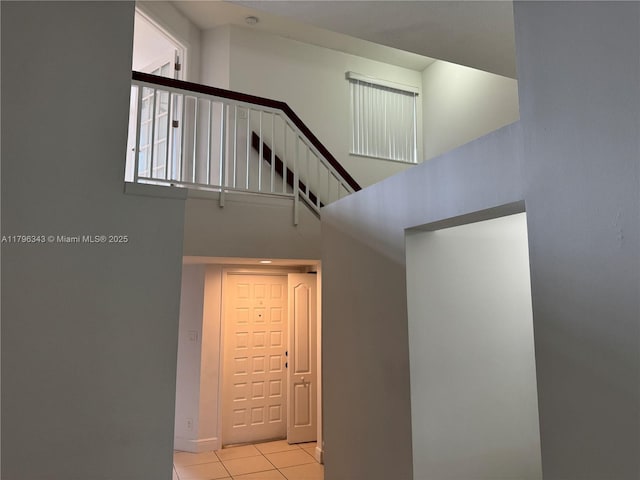 stairway featuring baseboards, a high ceiling, and tile patterned floors