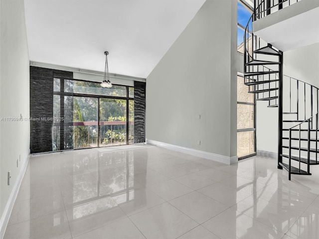 interior space with baseboards, a high ceiling, stairway, and expansive windows