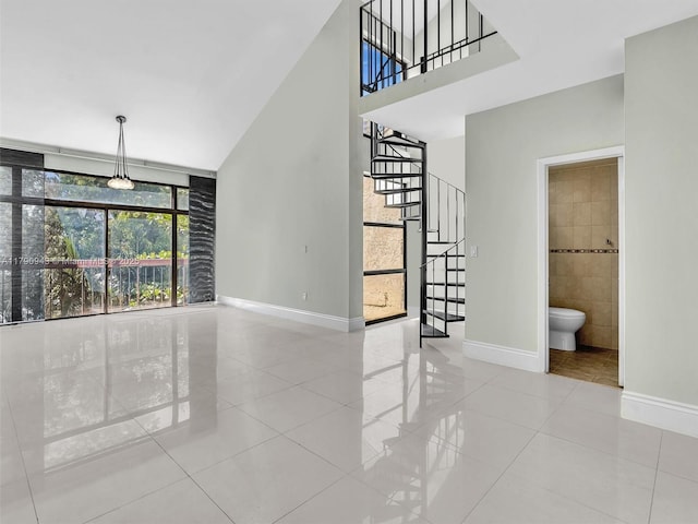 unfurnished living room featuring stairs, a high ceiling, baseboards, and tile patterned flooring