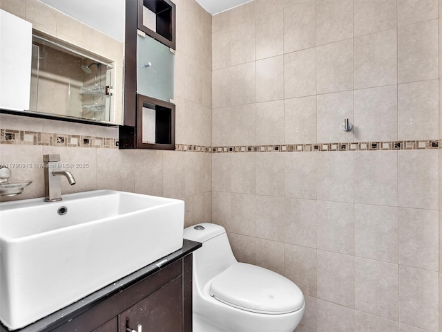 bathroom with vanity, walk in shower, toilet, and tile walls