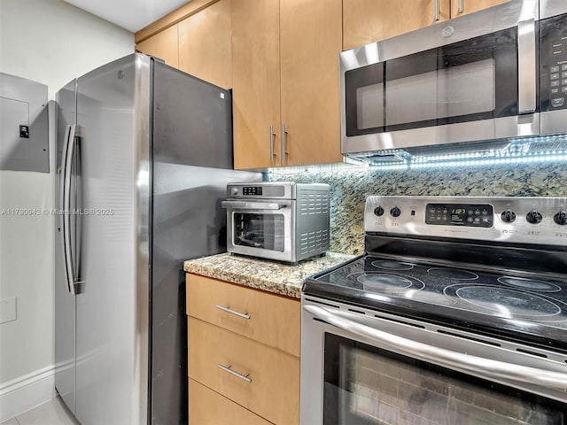 kitchen featuring a toaster, tasteful backsplash, light stone countertops, and stainless steel appliances