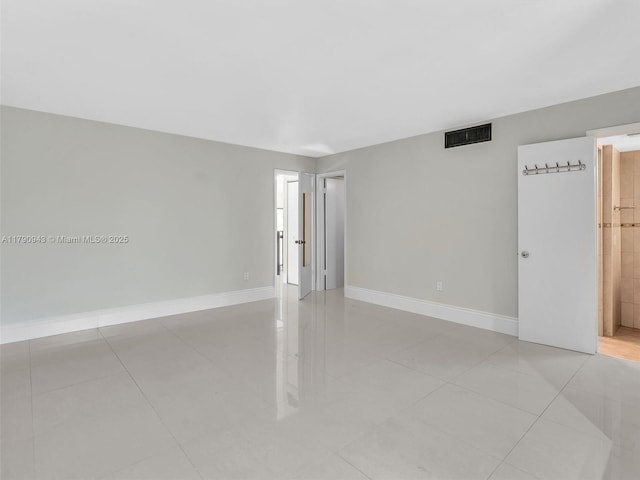 empty room with baseboards, visible vents, and light tile patterned floors