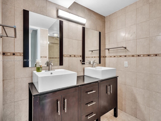 full bathroom with double vanity, tile walls, and a sink