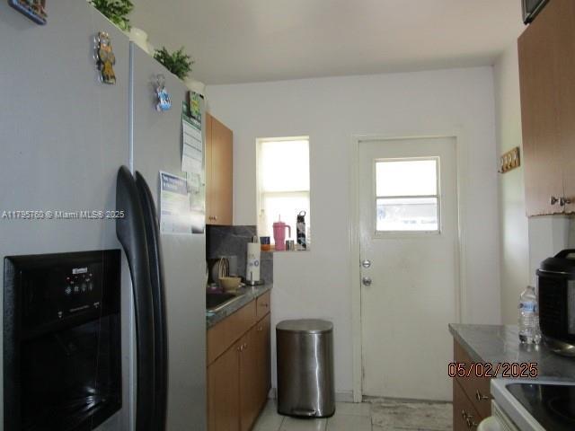kitchen featuring dark countertops, stainless steel fridge with ice dispenser, range, and a sink