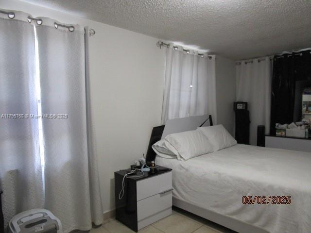 bedroom with a textured ceiling and light tile patterned flooring
