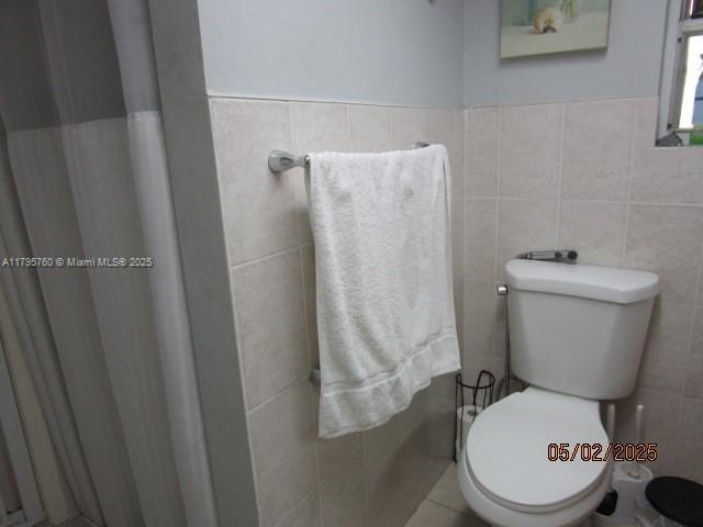 full bath with tile walls and toilet