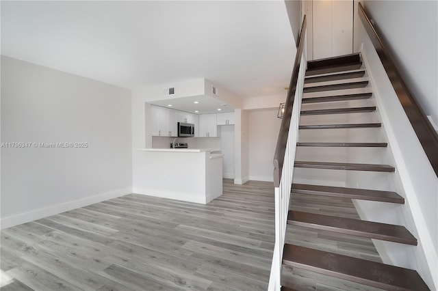 stairs featuring baseboards, visible vents, and wood finished floors