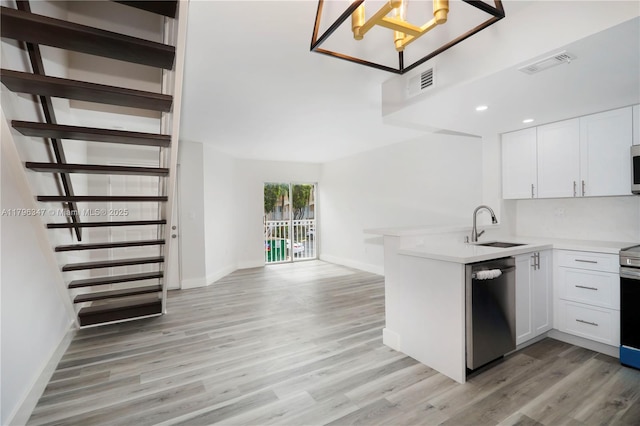 kitchen with light wood-style flooring, visible vents, a sink, a peninsula, and stainless steel appliances