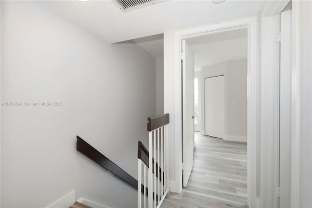 stairs with baseboards, visible vents, and wood finished floors