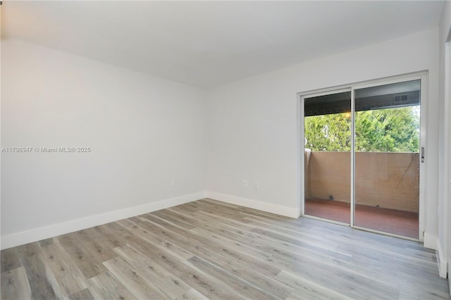 spare room with baseboards and light wood-style floors
