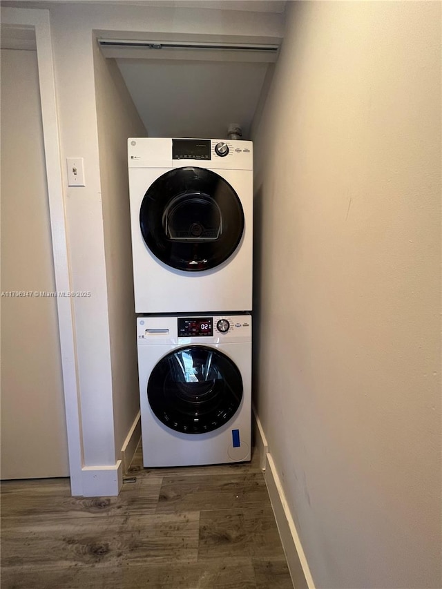 laundry area featuring baseboards, laundry area, stacked washer and clothes dryer, and wood finished floors