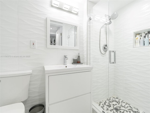 full bath with a shower stall, tile walls, vanity, and toilet