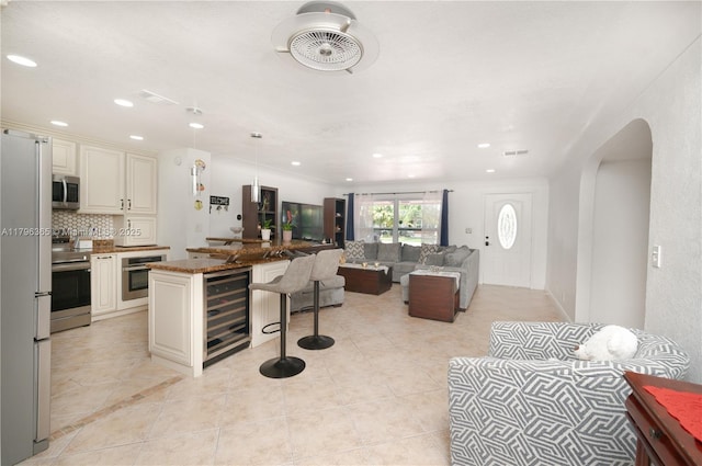717 E River Dr, Margate, FL 33063 - kitchen with appliances with stainless steel finishes, wine cooler, open floor plan, a kitchen bar, and arched walkways