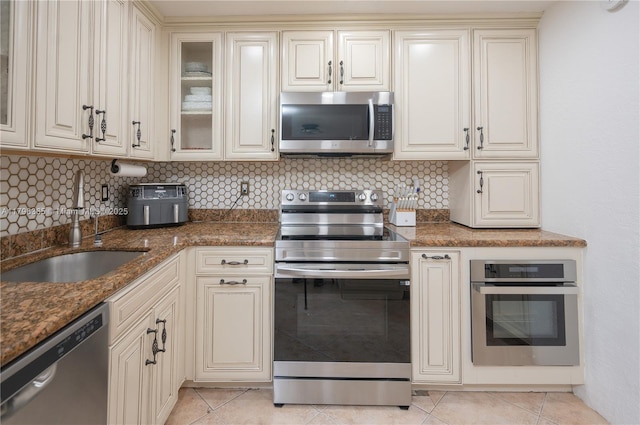 717 E River Dr, Margate, FL 33063 - kitchen featuring appliances with stainless steel finishes, cream cabinetry, and decorative backsplash