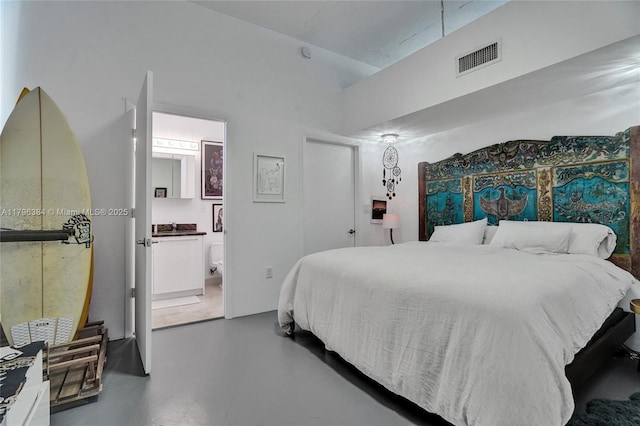 bedroom with ensuite bathroom, concrete floors, and visible vents
