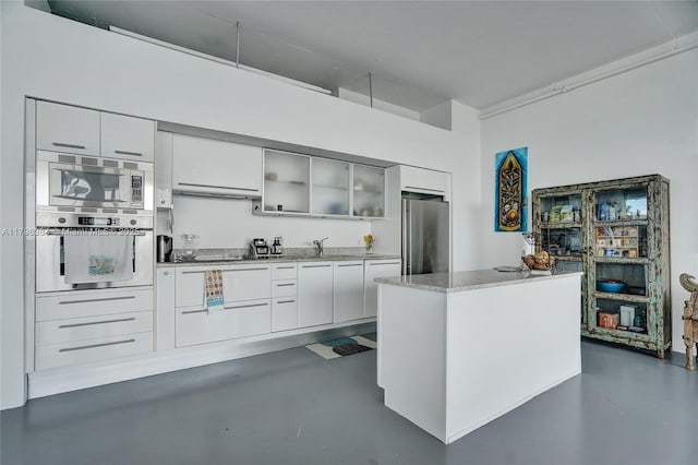 kitchen featuring concrete flooring, modern cabinets, white cabinets, and stainless steel appliances