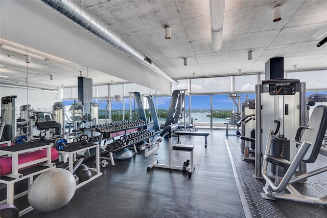 workout area featuring visible vents, a water view, and expansive windows