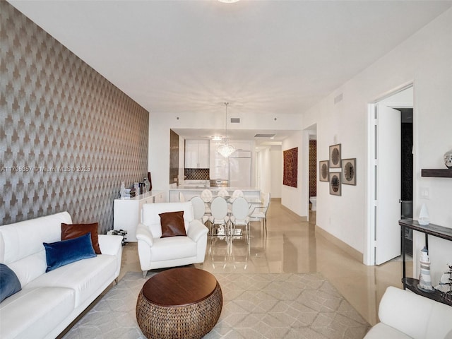 living area with wallpapered walls, an accent wall, baseboards, and light tile patterned floors