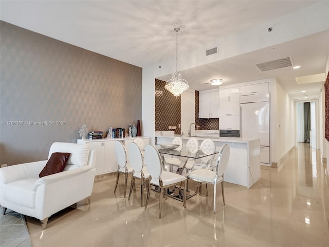 dining space featuring an accent wall, a chandelier, and wallpapered walls
