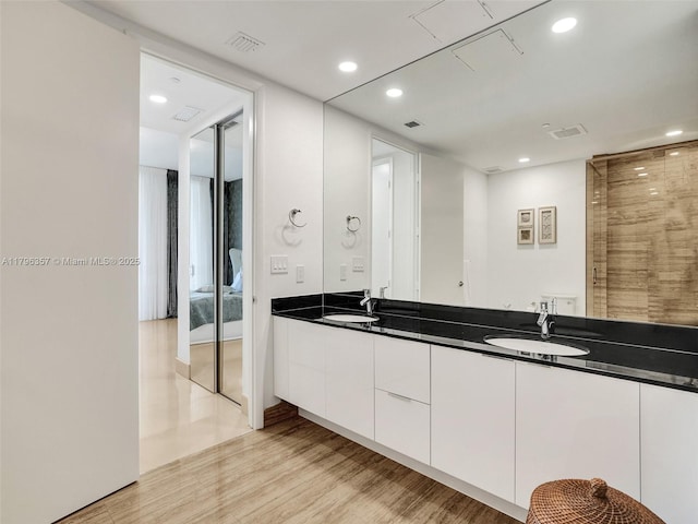 full bath with recessed lighting, double vanity, wood finished floors, and ensuite bathroom