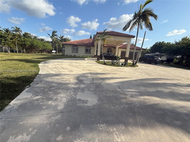 mediterranean / spanish-style house with curved driveway, a front lawn, stucco siding, and a tile roof