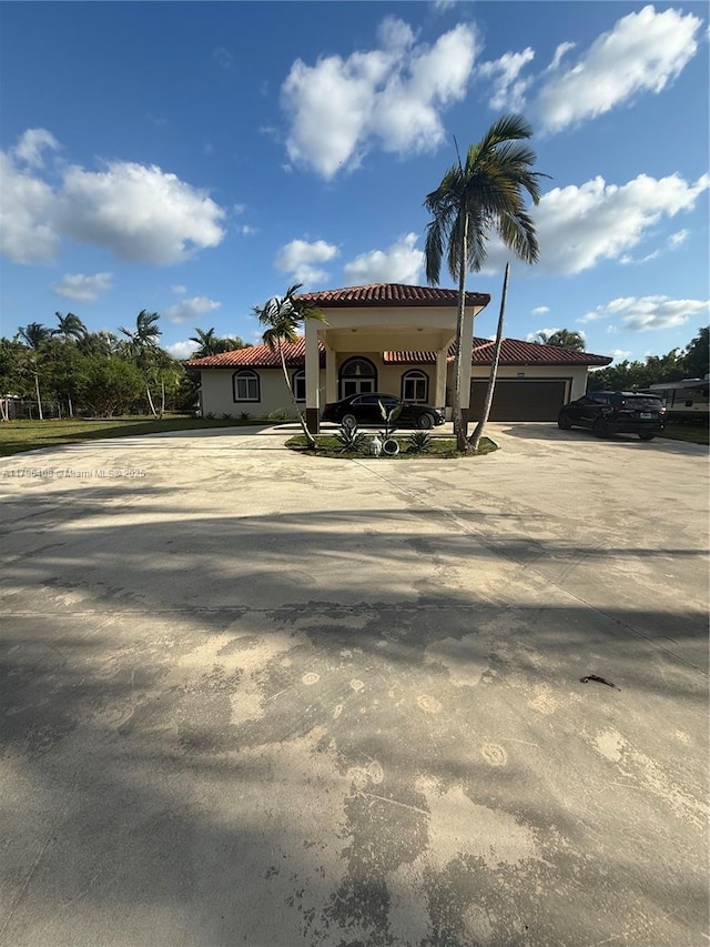 mediterranean / spanish-style home with concrete driveway, a tiled roof, an attached garage, and stucco siding