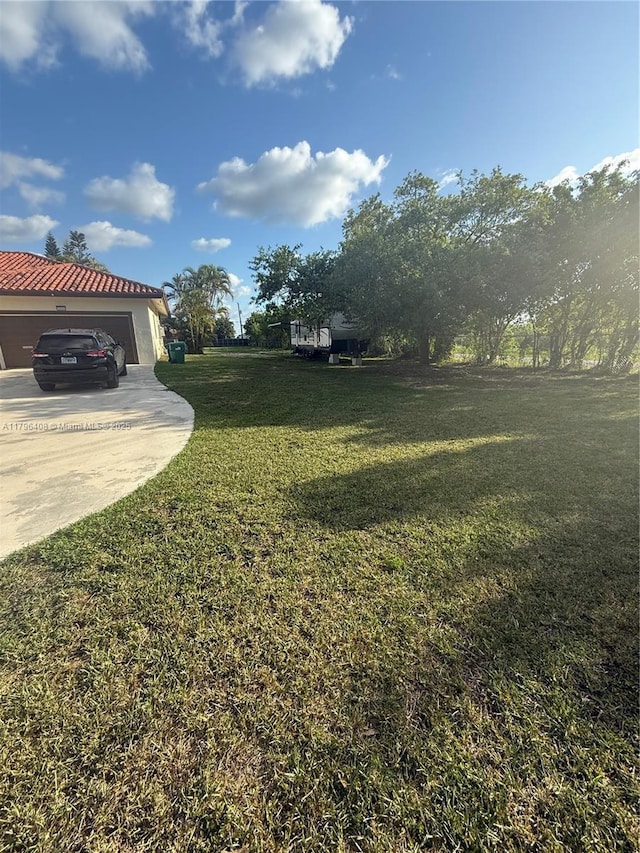 view of yard featuring driveway and a garage