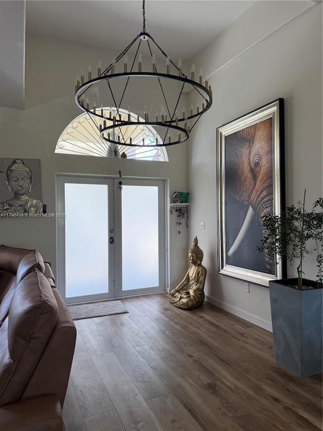 interior space featuring baseboards, french doors, a notable chandelier, and wood finished floors