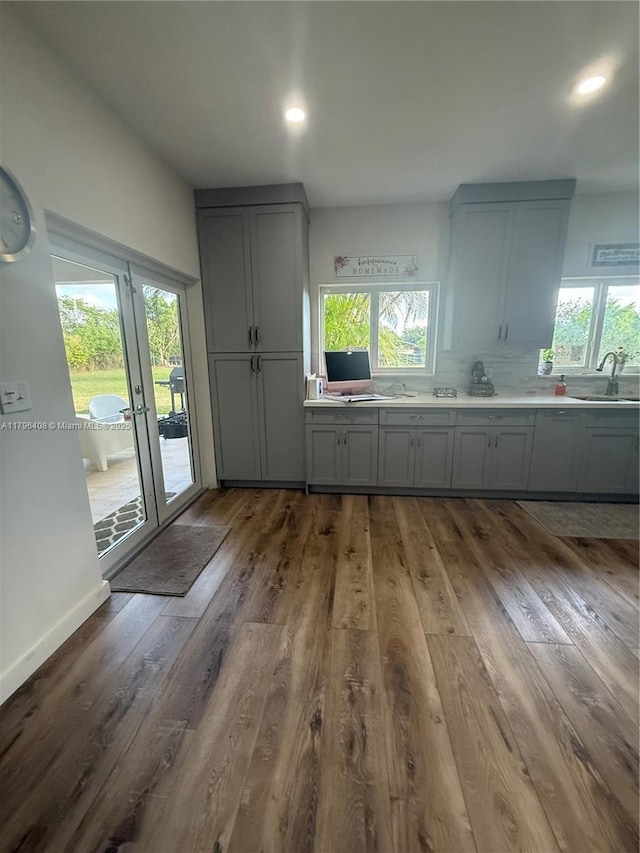 kitchen featuring decorative backsplash, gray cabinets, wood finished floors, a sink, and recessed lighting