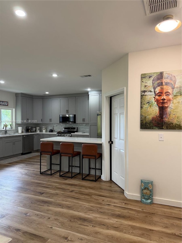 kitchen featuring appliances with stainless steel finishes, a sink, gray cabinets, decorative backsplash, and visible vents