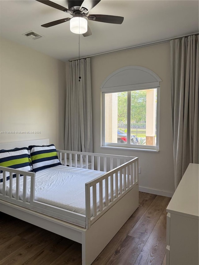 bedroom with baseboards, ceiling fan, visible vents, and wood finished floors