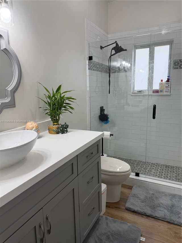 full bathroom featuring vanity, a stall shower, toilet, and wood finished floors