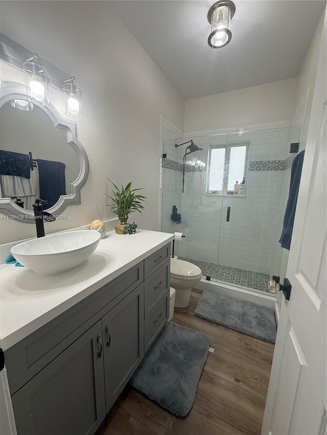 full bath featuring vanity, a stall shower, wood finished floors, and toilet