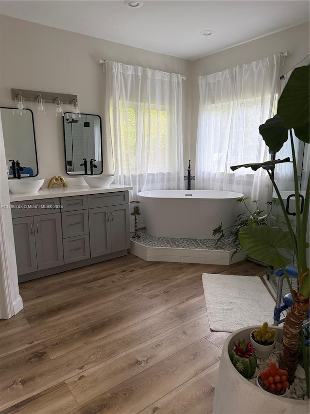 bathroom with vanity, a soaking tub, recessed lighting, and wood finished floors