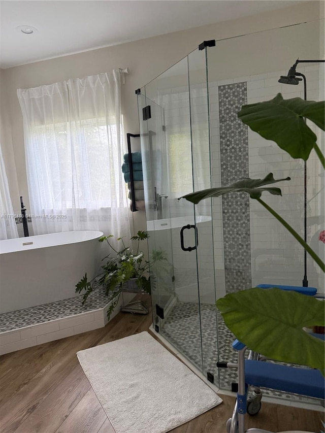 full bath with a freestanding bath, a shower stall, and wood finished floors