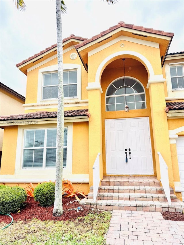 view of exterior entry with a tiled roof and stucco siding