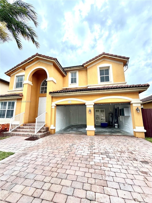 view of front of home featuring a tiled roof, decorative driveway, an attached garage, and stucco siding