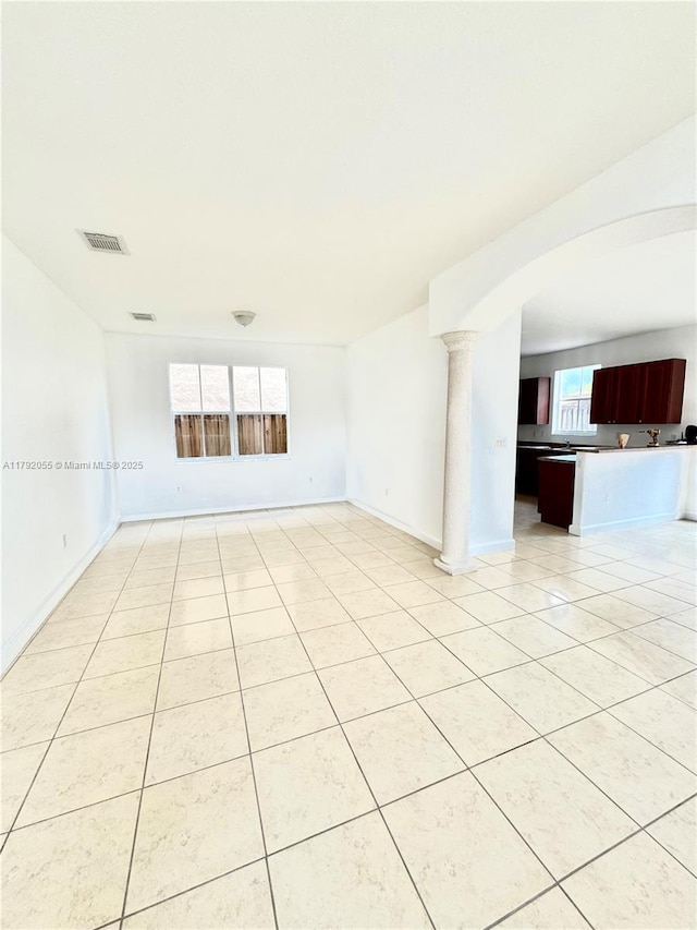 spare room featuring light tile patterned flooring, arched walkways, visible vents, and baseboards