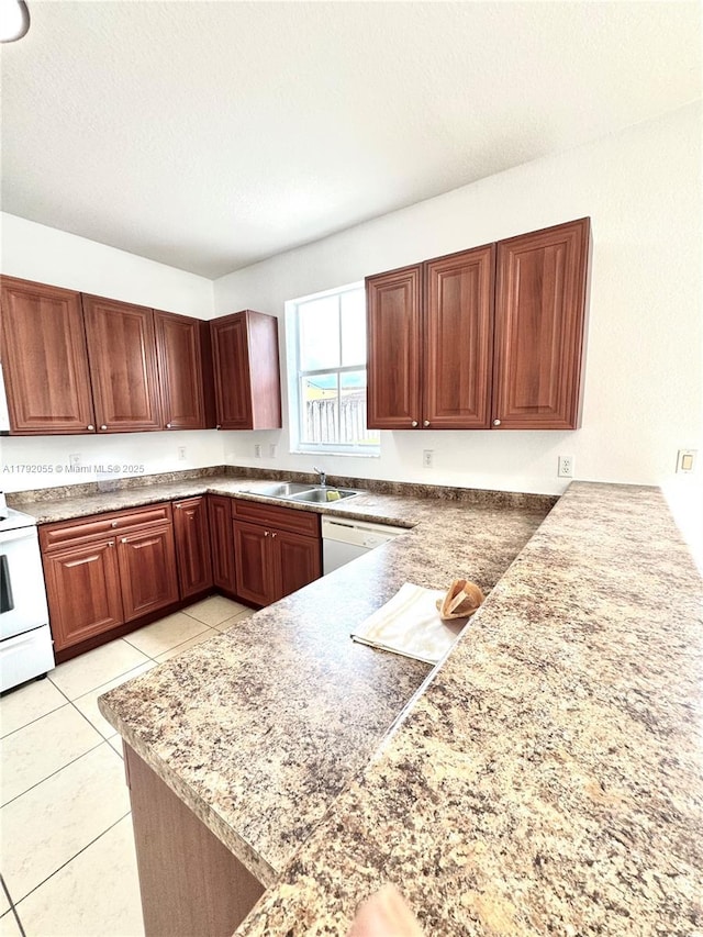kitchen with white appliances, a peninsula, light tile patterned flooring, and a sink