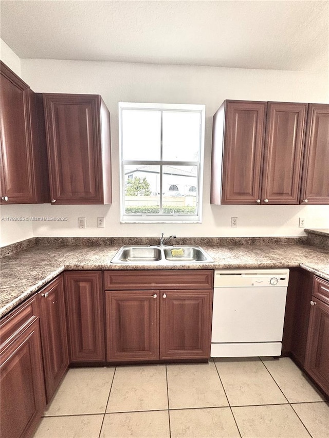 kitchen featuring white dishwasher, light tile patterned flooring, dark countertops, and a sink