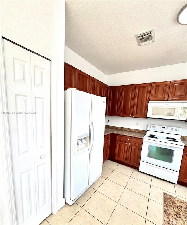 kitchen featuring a textured ceiling, white appliances, light tile patterned flooring, and visible vents