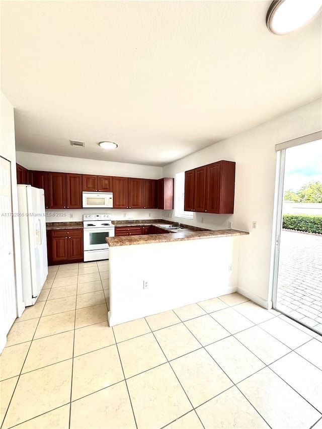 kitchen featuring visible vents, a peninsula, light tile patterned flooring, white appliances, and reddish brown cabinets