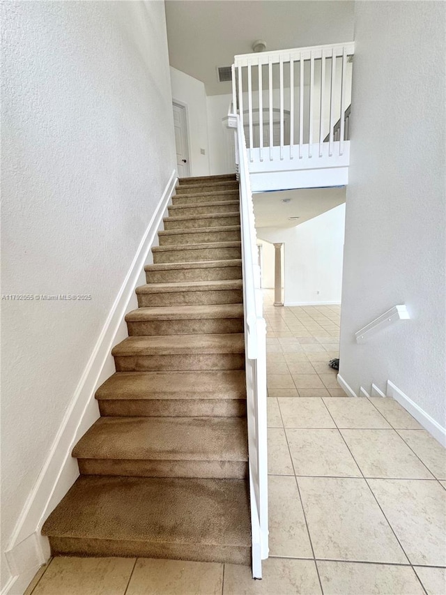 stairway with baseboards, tile patterned flooring, a textured wall, and visible vents