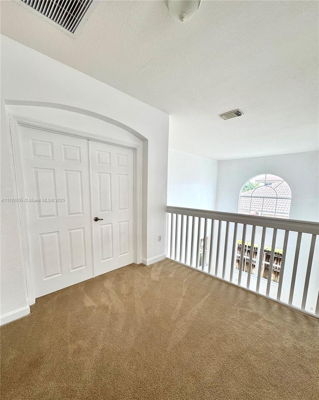 interior space featuring visible vents, carpet flooring, baseboards, and arched walkways