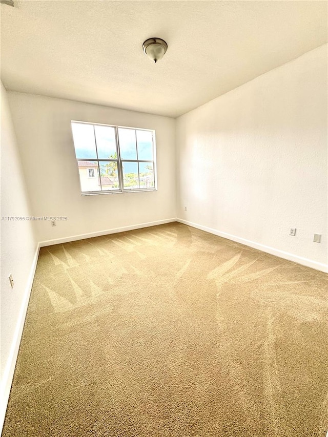 carpeted empty room featuring a textured ceiling, baseboards, and visible vents