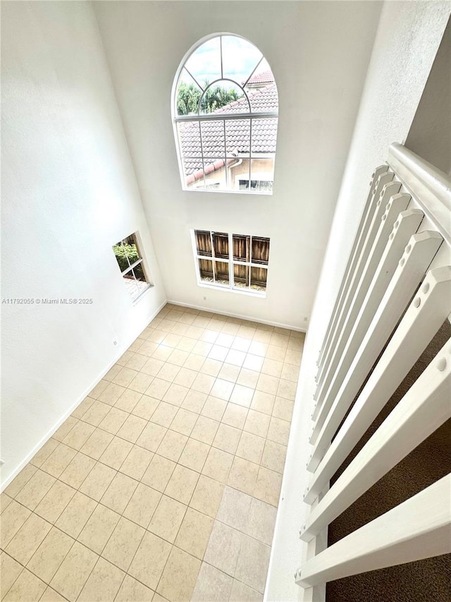 unfurnished living room with baseboards, tile patterned flooring, and a towering ceiling