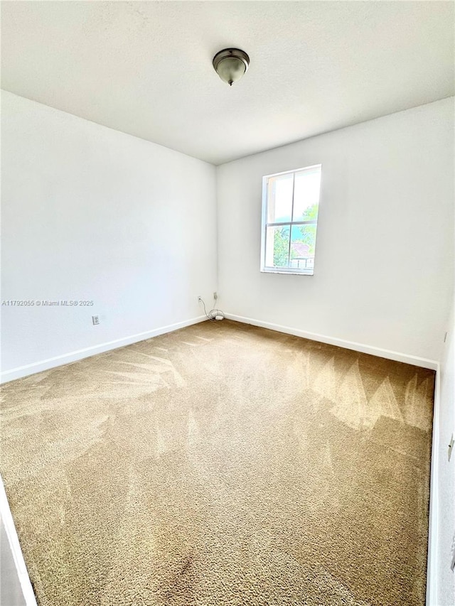 carpeted spare room featuring baseboards