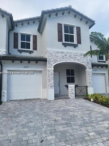 view of front of property with a garage, stucco siding, decorative driveway, and stone siding